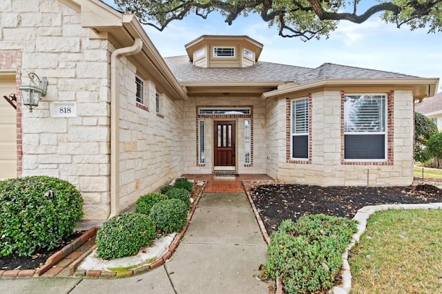 doorway to property featuring stone siding and a shingled roof