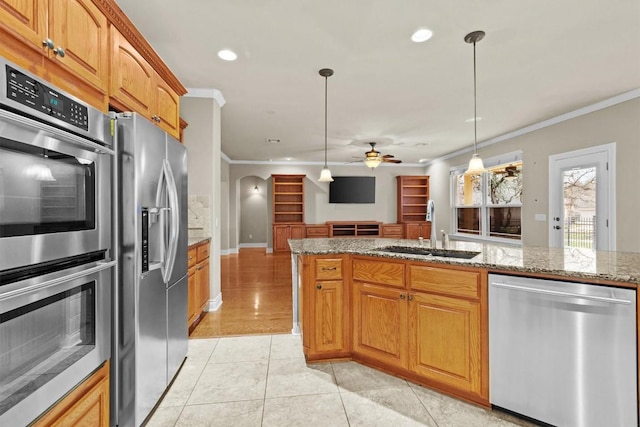 kitchen featuring arched walkways, a sink, open floor plan, appliances with stainless steel finishes, and crown molding