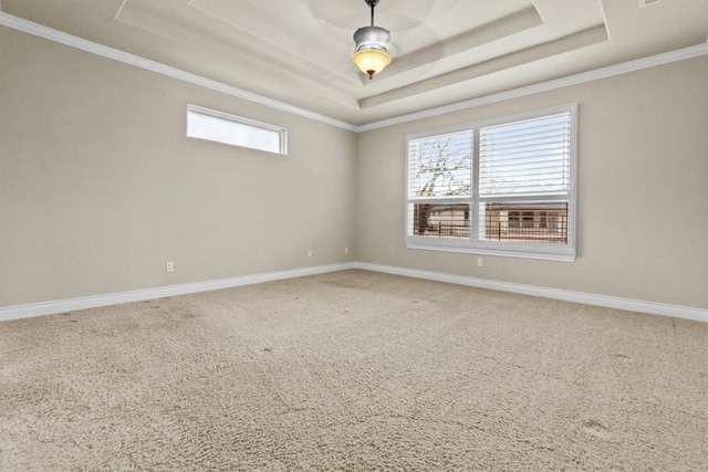 carpeted spare room featuring a tray ceiling, crown molding, and baseboards