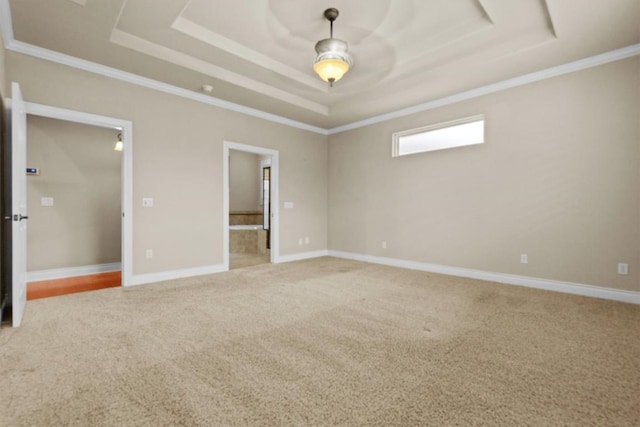 empty room featuring baseboards, a tray ceiling, ornamental molding, and light colored carpet