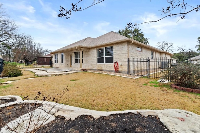 view of front of home with a shingled roof, stone siding, fence, a patio area, and a front lawn