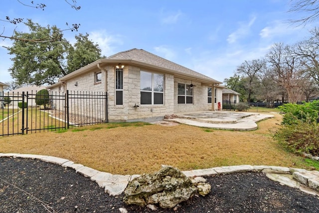 rear view of house with a yard, stone siding, a patio area, and fence