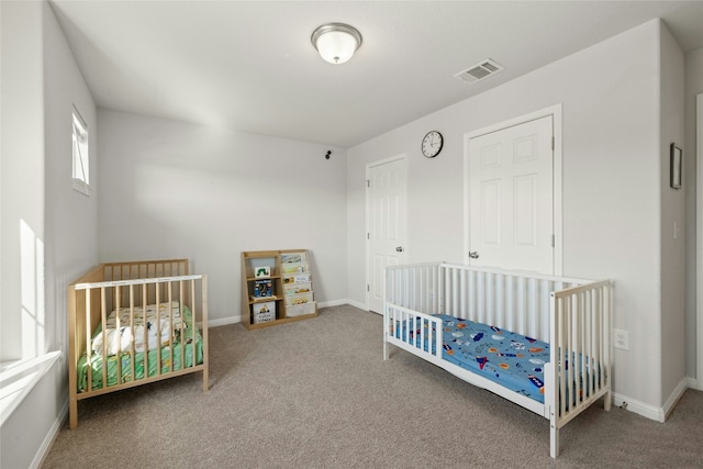 carpeted bedroom with a nursery area, visible vents, and baseboards