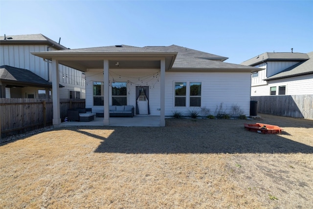 rear view of house with a fenced backyard and a patio