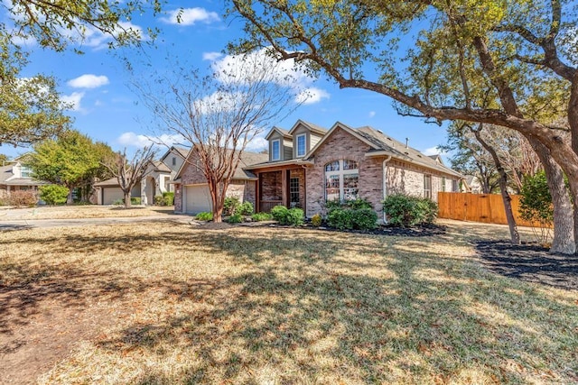 view of front of property featuring a garage, brick siding, fence, and a front lawn