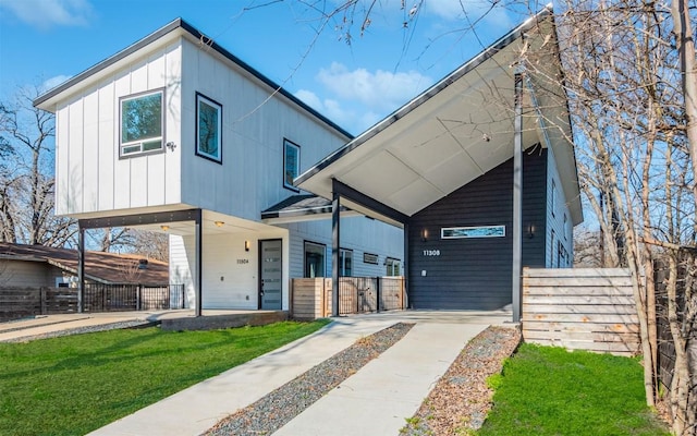 contemporary home featuring board and batten siding, a front lawn, and fence