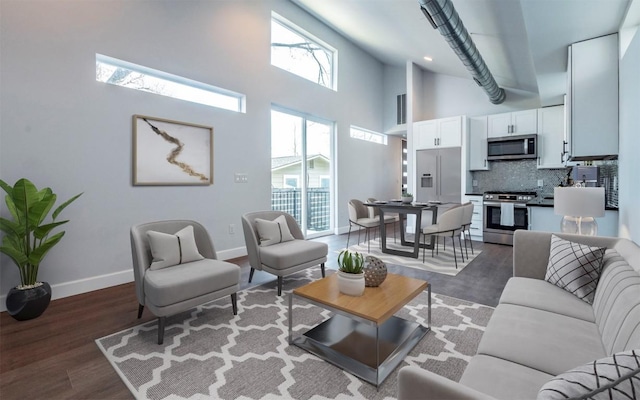 living room with visible vents, baseboards, high vaulted ceiling, and wood finished floors