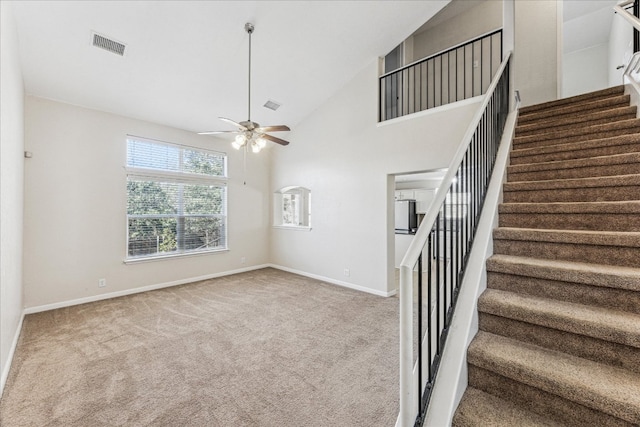 interior space featuring baseboards, visible vents, a ceiling fan, carpet floors, and high vaulted ceiling