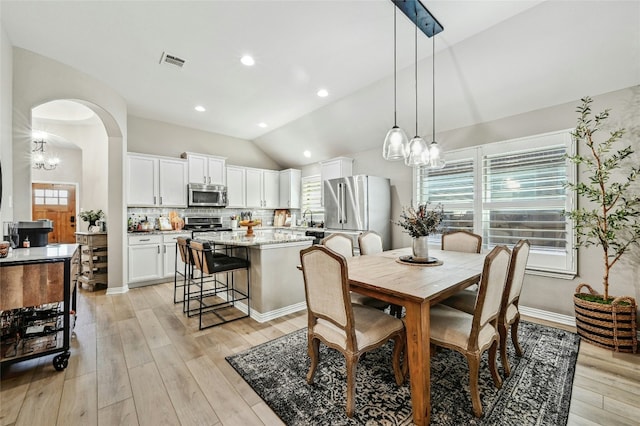 dining area featuring arched walkways, recessed lighting, visible vents, light wood-style floors, and vaulted ceiling