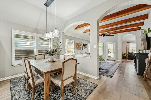 dining room with arched walkways, light wood-style flooring, and baseboards