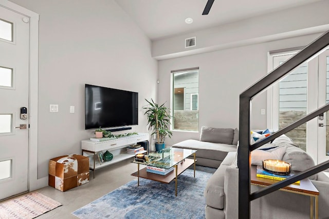 living room featuring vaulted ceiling, visible vents, concrete floors, and stairs
