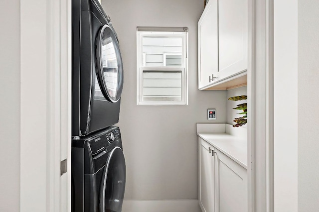 laundry room with cabinet space and stacked washer and clothes dryer