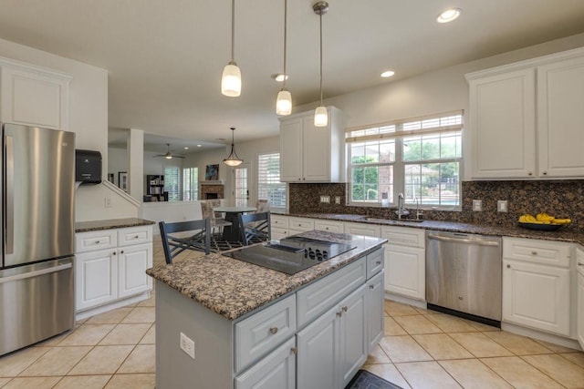 kitchen featuring stainless steel appliances, a sink, a center island, white cabinets, and decorative backsplash