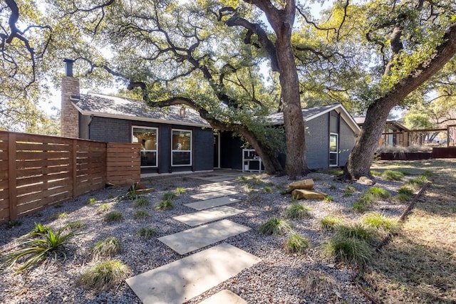 exterior space featuring brick siding, a chimney, and fence