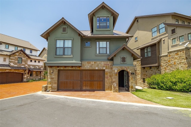 view of front of property featuring stucco siding, a standing seam roof, metal roof, a garage, and stone siding