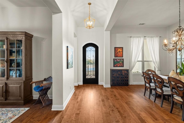 foyer with visible vents, arched walkways, wood-type flooring, and a notable chandelier