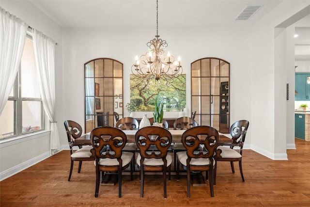 dining space with baseboards, wood finished floors, visible vents, and a notable chandelier