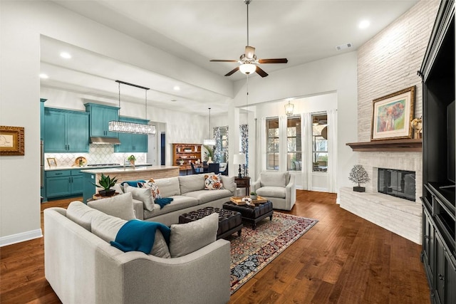 living area with baseboards, visible vents, dark wood finished floors, and a fireplace