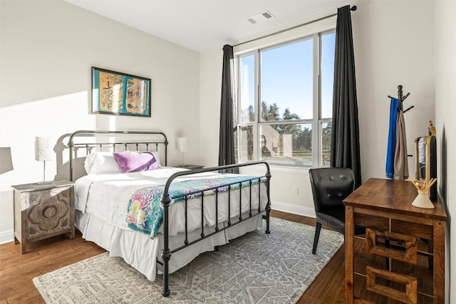 bedroom featuring baseboards, visible vents, and wood finished floors