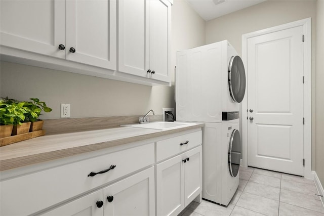 washroom with a sink, cabinet space, light tile patterned floors, and stacked washer / drying machine