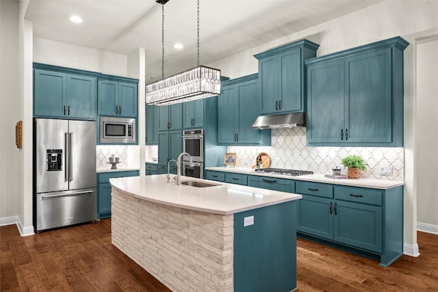 kitchen with blue cabinets, appliances with stainless steel finishes, a sink, and under cabinet range hood