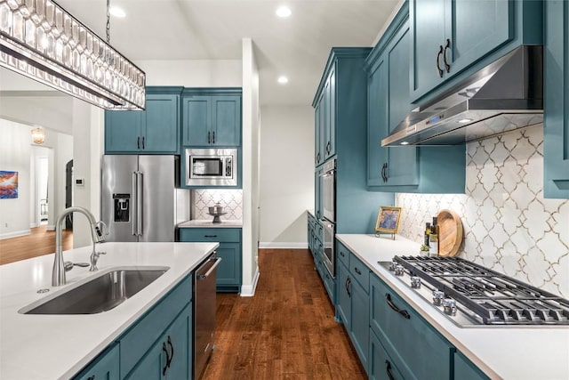 kitchen featuring under cabinet range hood, appliances with stainless steel finishes, blue cabinetry, and a sink