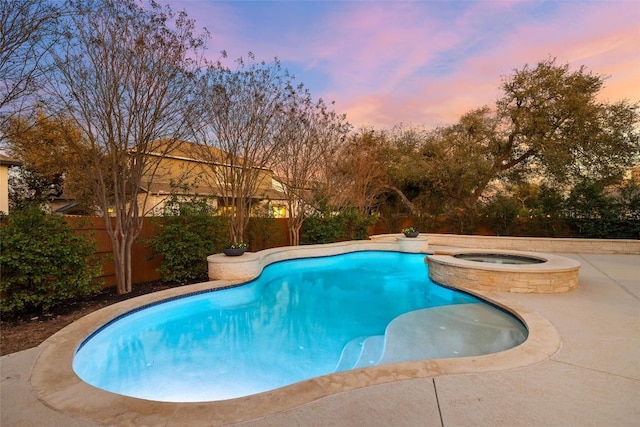 pool at dusk featuring a patio area, a fenced backyard, and a pool with connected hot tub