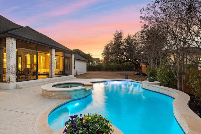 pool at dusk featuring a patio and a pool with connected hot tub