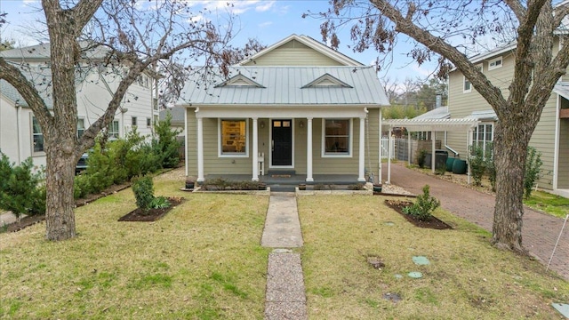 bungalow featuring covered porch, metal roof, a front yard, and driveway