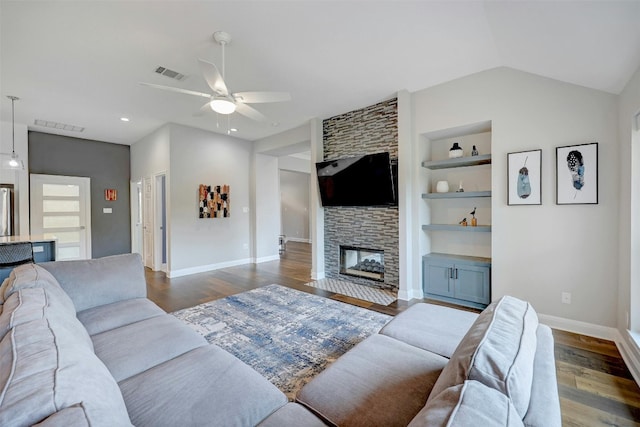 living area featuring baseboards, visible vents, dark wood-style flooring, a stone fireplace, and built in shelves