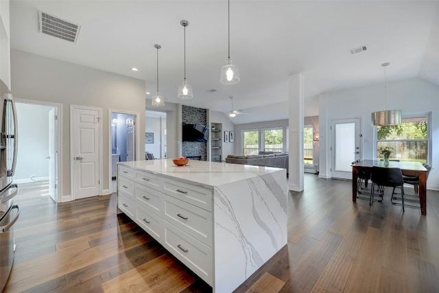 kitchen with a center island, pendant lighting, visible vents, open floor plan, and white cabinets