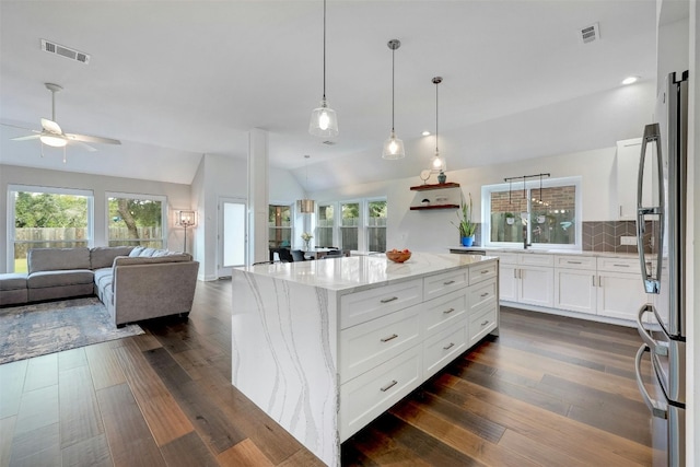 kitchen featuring white cabinets, light stone countertops, visible vents, and open floor plan