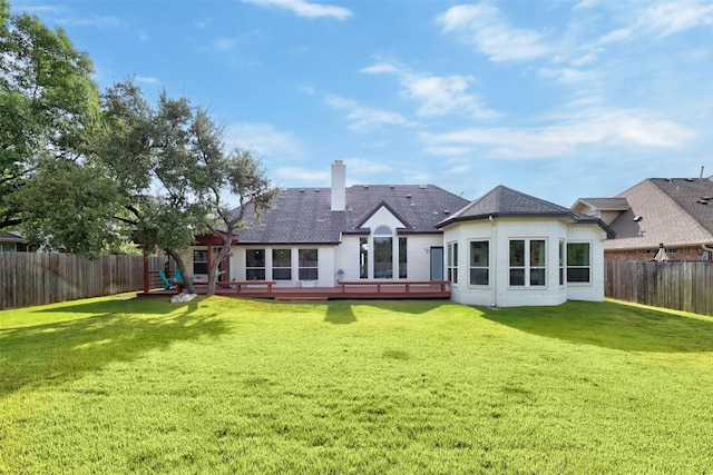 back of house with a fenced backyard, a chimney, a wooden deck, and a lawn