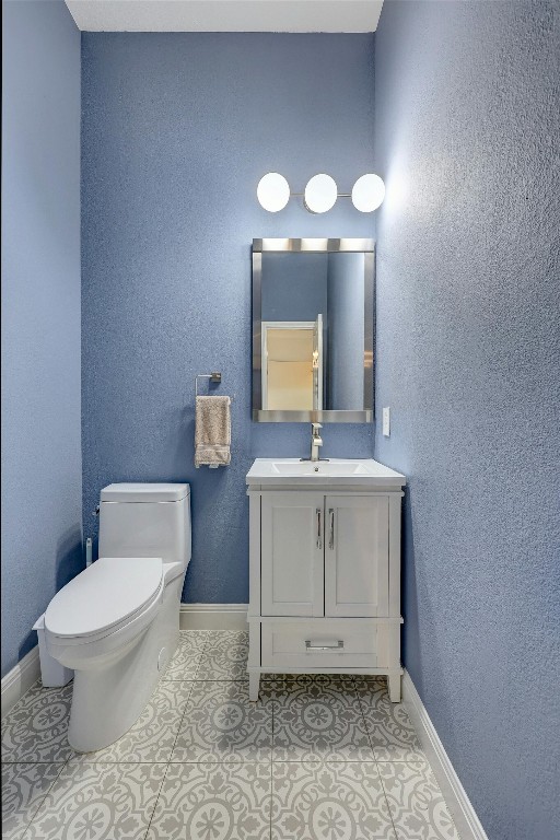 half bath featuring toilet, baseboards, vanity, and tile patterned floors