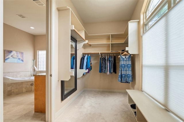 spacious closet with light carpet, light tile patterned floors, and visible vents