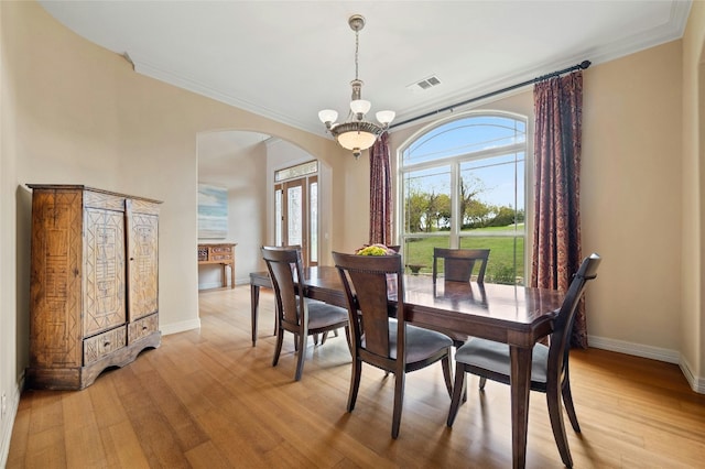 dining room featuring crown molding, a notable chandelier, light wood finished floors, visible vents, and baseboards