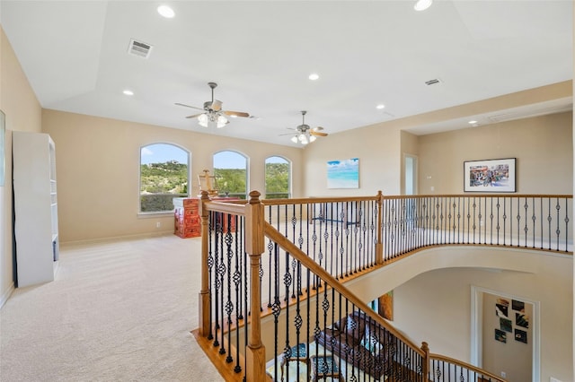 hallway with light carpet, recessed lighting, visible vents, and an upstairs landing