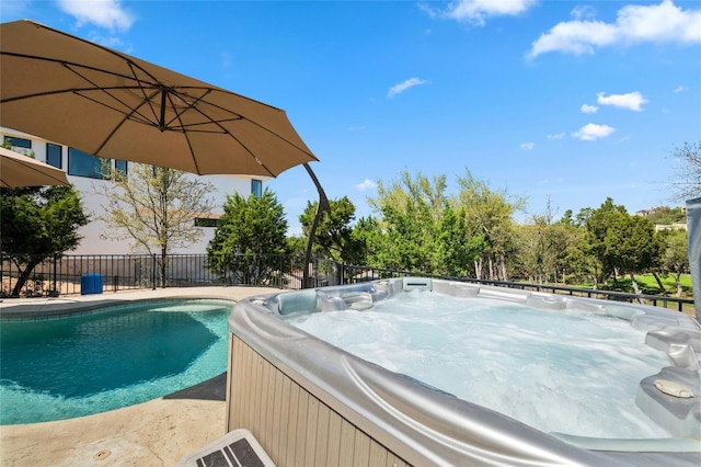 view of swimming pool featuring a hot tub and fence