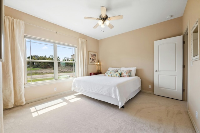 bedroom with light colored carpet, ceiling fan, and baseboards