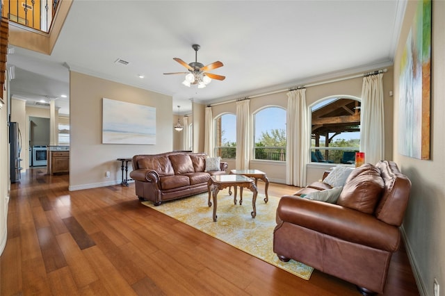 living area featuring crown molding, baseboards, ceiling fan, and wood finished floors