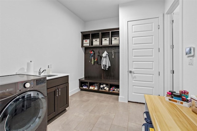 washroom with cabinet space, baseboards, washer / clothes dryer, and a sink