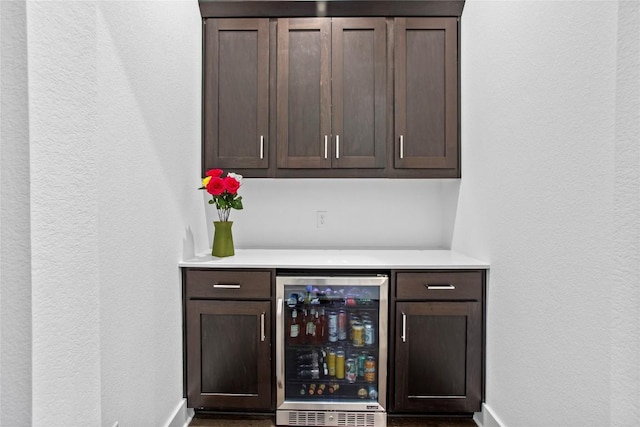 bar featuring beverage cooler, baseboards, and a bar