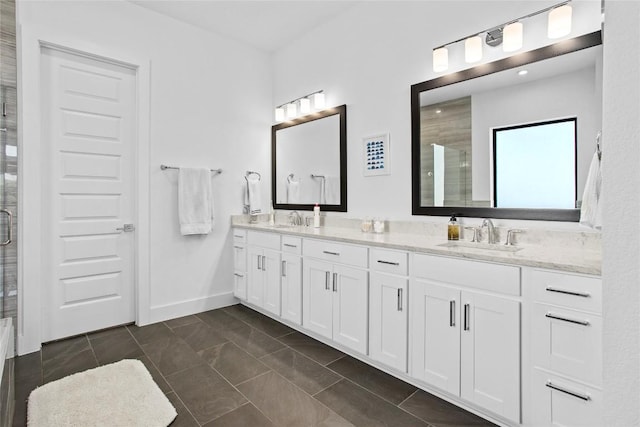 bathroom with double vanity, baseboards, a tile shower, and a sink