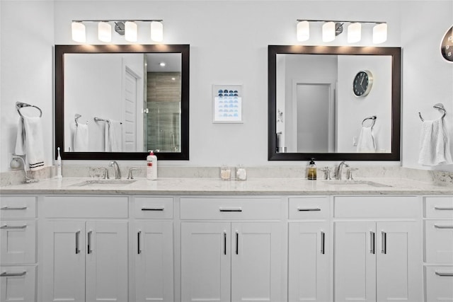 bathroom featuring a tile shower, double vanity, and a sink