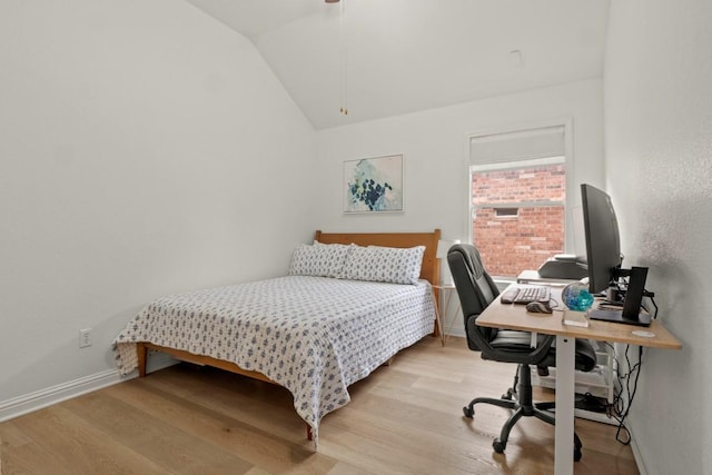 bedroom with lofted ceiling, light wood finished floors, and baseboards