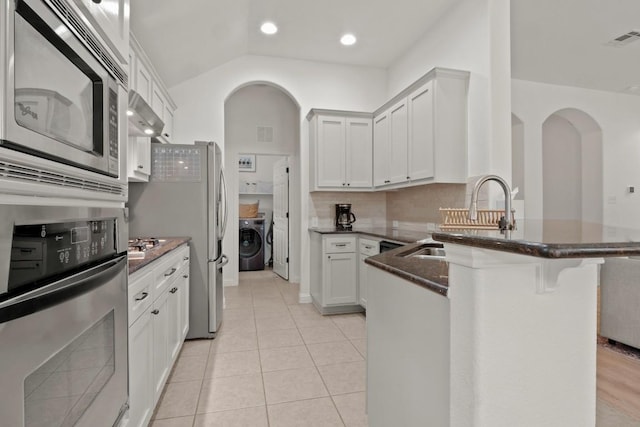 kitchen featuring stainless steel appliances, visible vents, white cabinets, washer / dryer, and a kitchen breakfast bar