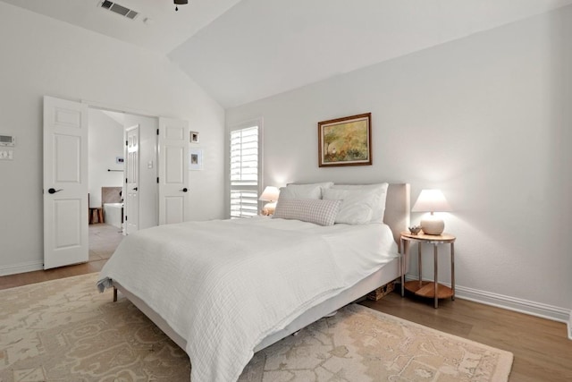 bedroom with baseboards, visible vents, connected bathroom, lofted ceiling, and wood finished floors