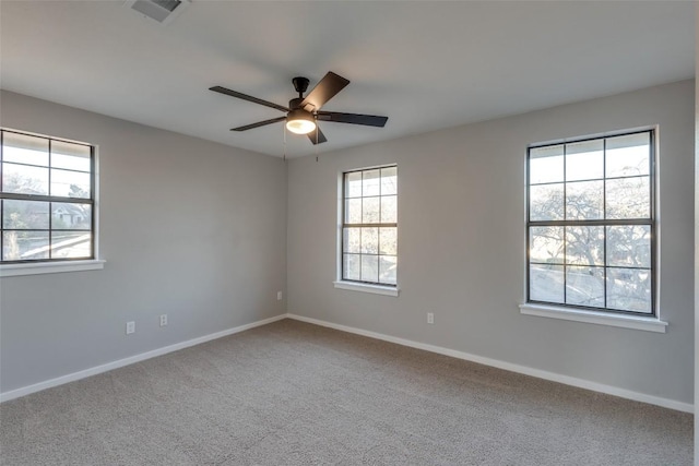 carpeted spare room with a ceiling fan, visible vents, and baseboards