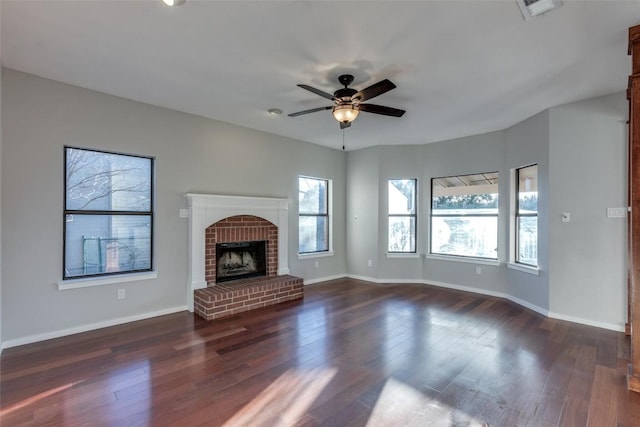 unfurnished living room with a healthy amount of sunlight, a fireplace, dark wood finished floors, and a ceiling fan