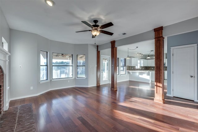 unfurnished living room with wood finished floors, a ceiling fan, visible vents, ornate columns, and a fireplace
